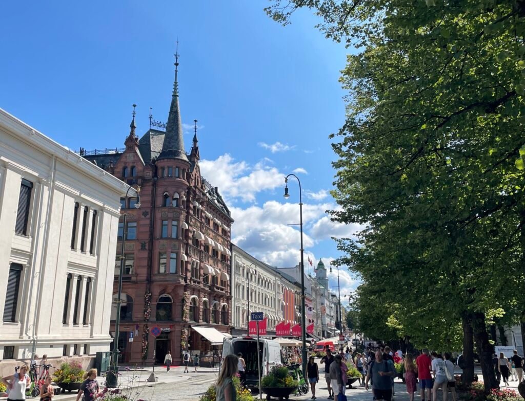 Centro di Oslo con edifici storici affacciati su una strada pedonale animata in una giornata di sole