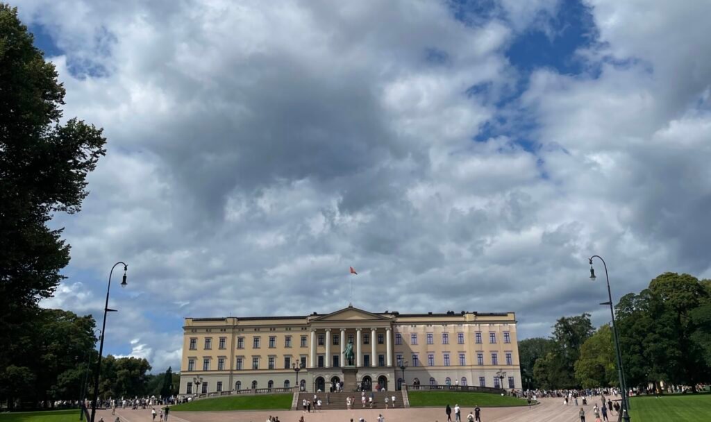 Palazzo Reale di Oslo visto dalla piazza antistante, con visitatori e cielo nuvoloso