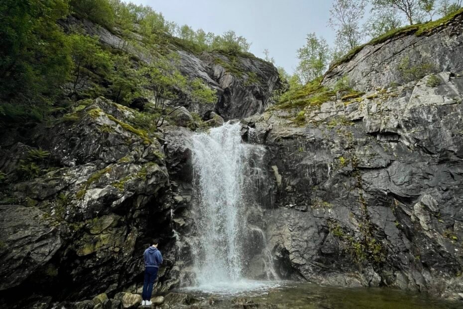 Cascata nei pressi di Lysebotn, in Jæren, che scende lungo una parete rocciosa con una persona in primo piano