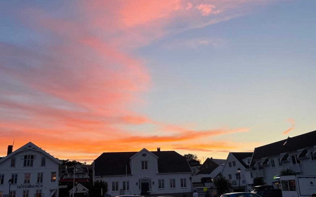 Tramonto a Lillesand, in Agder, con cielo rosa e arancione sopra le case del centro cittadino