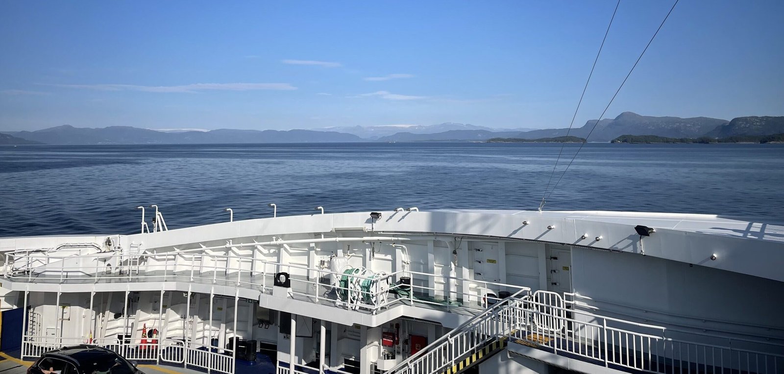 Vista dal ponte di un traghetto sul fiordo norvegese, con mare calmo e montagne all’orizzonte